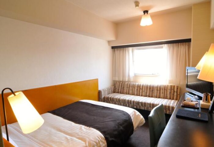 Hotel Listel Shinjuku's gay-friendly room. Features a double bed, striped sofa, desk, and lamp. A comfortable stay in Shinjuku, Japan.