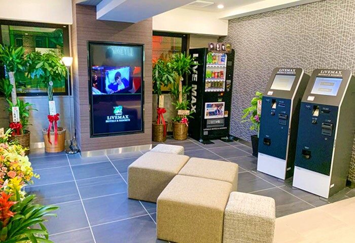 Hotel Livemax Shinjuku-Kabukicho lobby. Vending machine, check-in kiosks, seating, and TV screen. Gay-friendly hotel in Shinjuku, Japan.