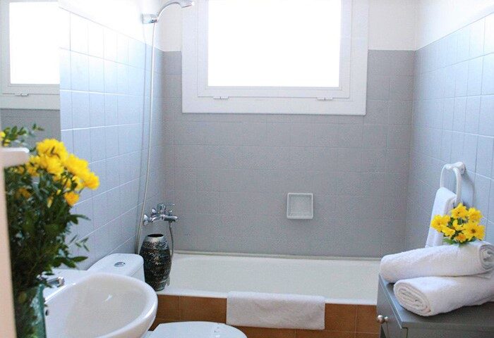 Bathroom at Gay-Friendly Hotel Los Globos. Bathtub, sink, and yellow flowers create a welcoming space for gay travelers. Hotel Los Globos.