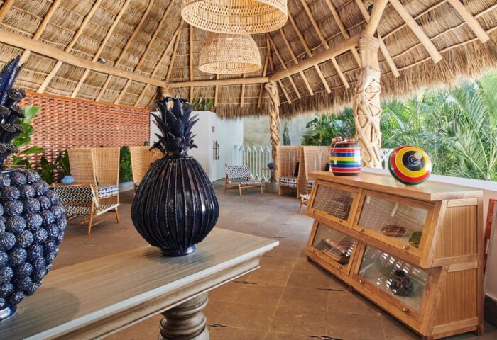 Hotel Luxury Patio Azul's gay-friendly design. Thatched roof, wicker lamps, and blue pineapple decor. Colorful accents. Relaxed, stylish vibe.