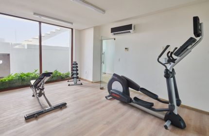 Hotel Luxury Patio Azul's gym. Gay-friendly hotel features fitness equipment: elliptical machine, weight bench, and dumbbells. Modern, clean space.