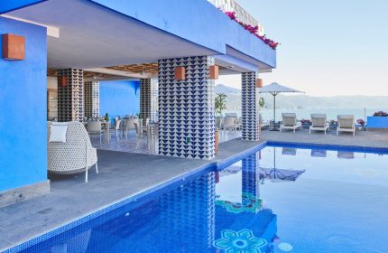 Hotel Luxury Patio Azul's gay-friendly appeal: poolside view of the patio, dining area, lounge chairs, and ocean. A vibrant, relaxing space.