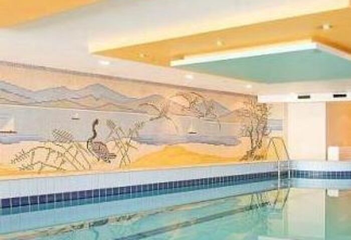 Hotel Lyskirchen's indoor pool. A gay-friendly hotel with a swimming pool and a mural of a lake with mountains and a bird. Cologne, Germany.