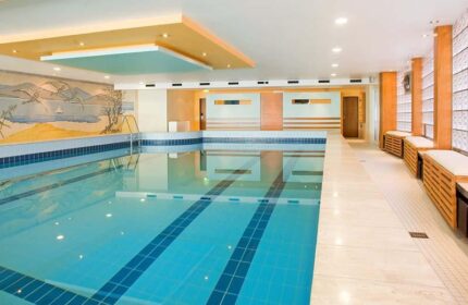 Hotel Lyskirchen's indoor pool, a gay-friendly hotel. Blue tiled pool with benches. A relaxing space for gay travelers in Cologne.
