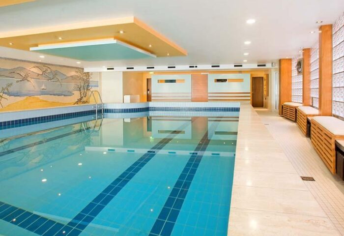 Hotel Lyskirchen's indoor pool, a gay-friendly hotel. Blue tiled pool with benches. A relaxing space for gay travelers in Cologne.