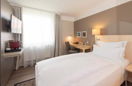 Hotel Lyskirchen gay-friendly room. Modern interior with bed, desk, TV, and coffee maker. Ideal for gay men's travel in Cologne.