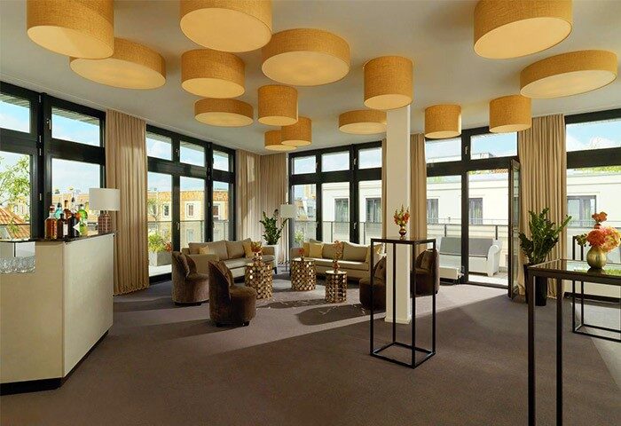 Hotel MANI by AMANO's lounge area. Gay-friendly hotel with stylish lighting, seating, bar, and outdoor terrace. Modern interior design.