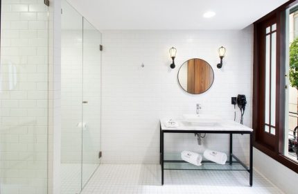Hotel MX mas reforma gay-friendly bathroom. Modern design with glass shower, round mirror, and marble sink. Stylish and clean for gay travelers.