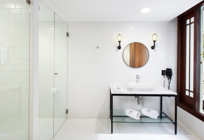 Hotel MX mas reforma gay-friendly bathroom. Modern design with glass shower, round mirror, and marble sink. Stylish and clean for gay travelers.