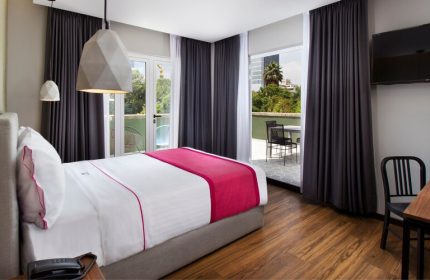 Hotel MX mas reforma gay-friendly room. A bed with a pink runner, balcony, desk, and geometric lights. Perfect for gay travel.