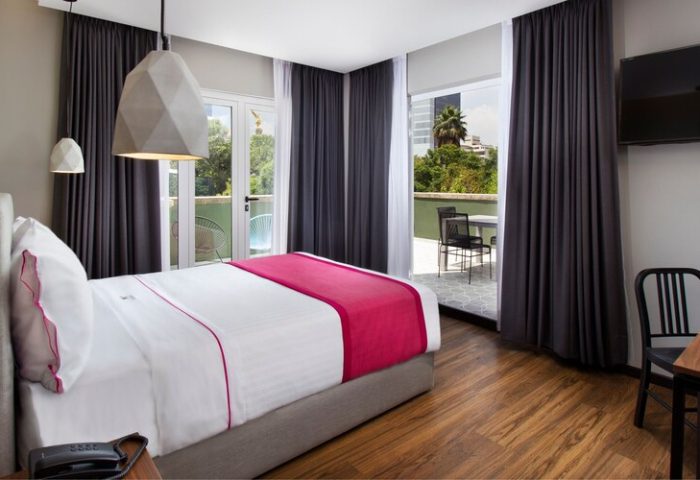 Hotel MX mas reforma gay-friendly room. A bed with a pink runner, balcony, desk, and geometric lights. Perfect for gay travel.