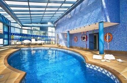 Indoor pool at the gay-friendly Hotel Madeira Centro. Blue tiled walls, lounge chairs, and a bright, inviting atmosphere.