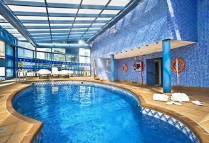 Indoor pool at the gay-friendly Hotel Madeira Centro. Blue tiled walls, lounge chairs, and a bright, inviting atmosphere.