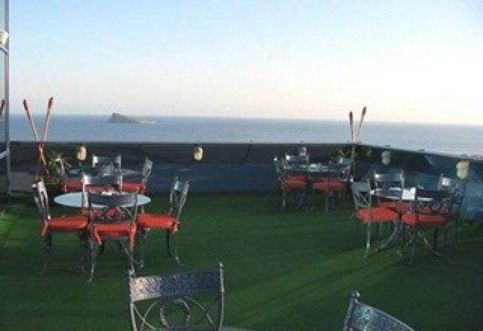 Hotel Madeira Centro's rooftop terrace with ocean view. Gay-friendly hotel with tables and chairs on the top floor.