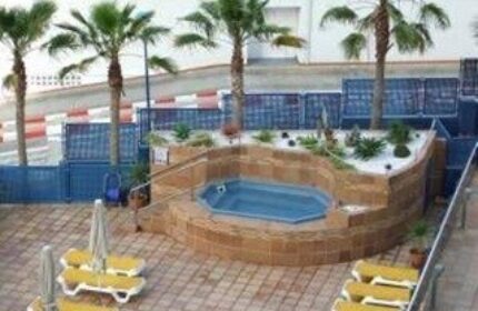 Hotel Madeira Centro's gay-friendly outdoor pool area. Palm trees, lounge chairs, and a jacuzzi tub create a relaxing atmosphere.
