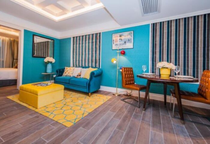 Hotel Madera Hollywood gay-friendly hotel room. Turquoise walls, blue sofa, yellow ottoman, and dining area. Upscale design for gay travelers.