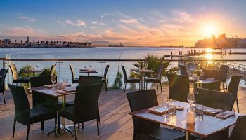 Hotel Maya A Doubletree Hotel's gay-friendly outdoor dining area at sunset. Tables set for dinner overlook the ocean. A romantic spot.