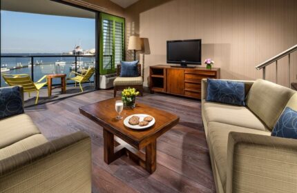 Hotel Maya A Doubletree Hotel suite living room with harbor view. Gay-friendly hotel with balcony, chairs, and coffee table. Perfect for gay travel.