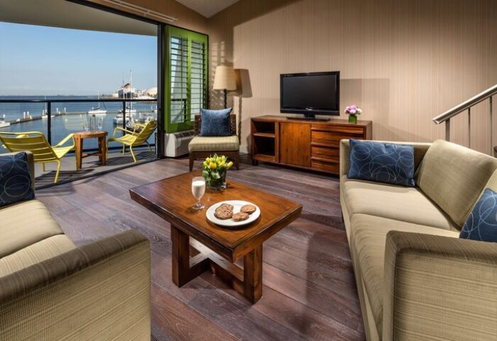 Hotel Maya A Doubletree Hotel suite living room with harbor view. Gay-friendly hotel with balcony, chairs, and coffee table. Perfect for gay travel.