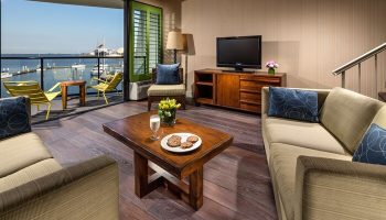Hotel Maya A Doubletree Hotel suite living room with harbor view. Gay-friendly hotel with balcony, chairs, and coffee table. Perfect for gay travel.