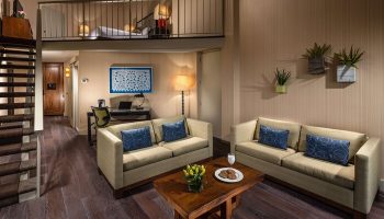 Hotel Maya A Doubletree Hotel suite interior. Gay-friendly hotel room with loft bed, sofas, desk, and modern decor. Ideal for gay travel.