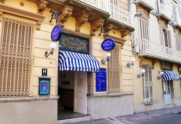 Hotel Medium Romantic exterior. Gay-friendly hotel with blue and white striped awning. Facade of the Hotel Romantic, a welcoming spot for gay travelers.