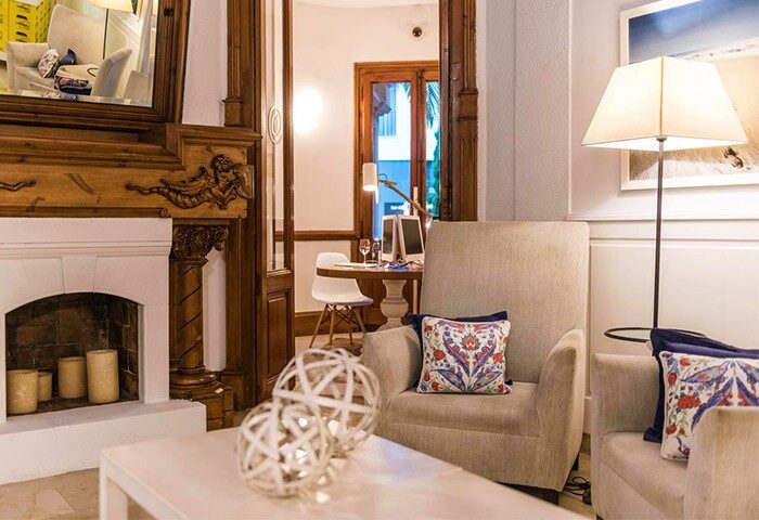 Hotel Medium Sitges Park's gay-friendly ambiance. Cozy seating area with fireplace, armchairs, and stylish decor. Relax at this Sitges hotel.