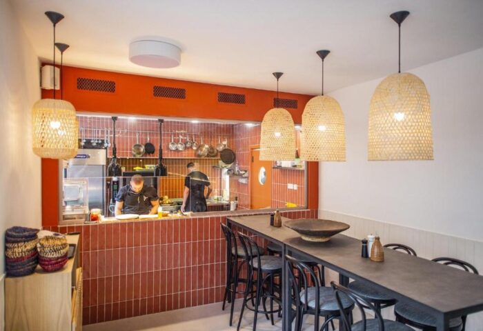 Hotel Memories Budapest's gay-friendly restaurant. Chefs work in the kitchen. Wicker lamps hang above a long table with black chairs.