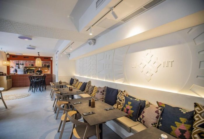 Hotel Memories Budapest's gay-friendly restaurant. Interior view of the dining area with tables, chairs, and decorative pillows. Modern design.