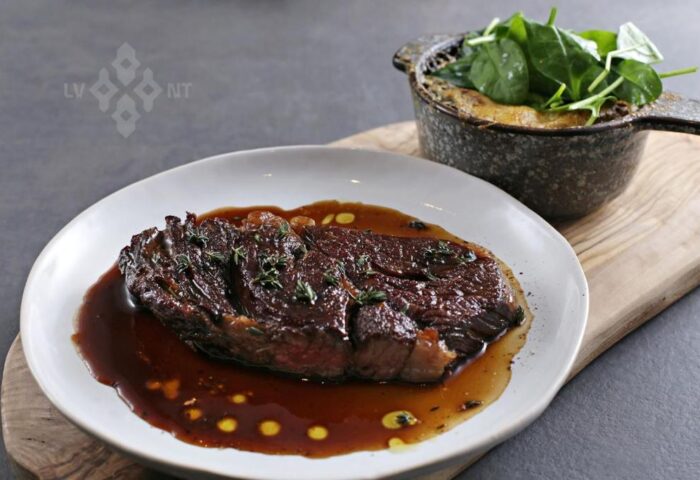 Fine dining at gay-friendly Hotel Memories Budapest. Steak with sauce, herbs, and spinach gratin. Delicious food for gay travelers.