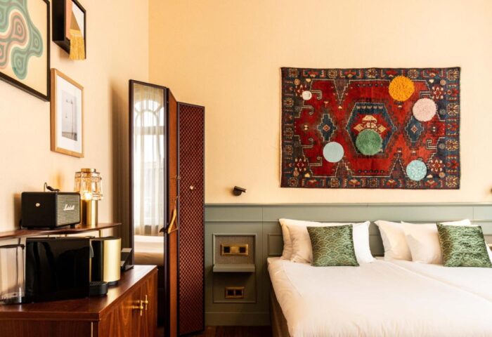 Hotel Mercier gay-friendly room. Bedroom interior with double bed, colorful rug, and modern decor. Gay travel lodging in Amsterdam.