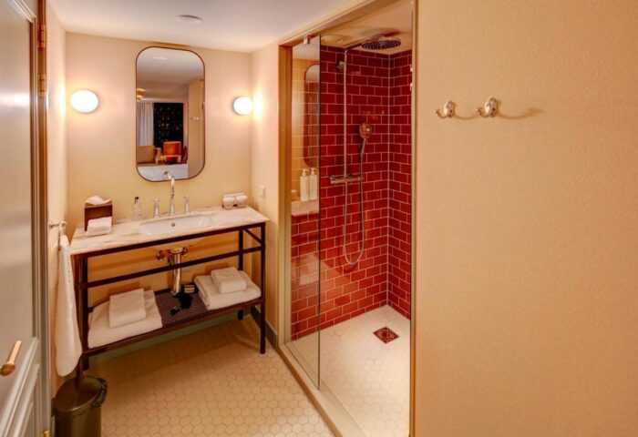 Hotel Mercier's stylish bathroom. Sink with marble top, red tiled shower. Gay-friendly hotel with modern design for gay travelers.
