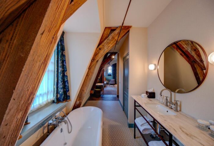 Hotel Mercier gay-friendly room. Bathroom with tub, sink, and exposed beams. Unique design in a boutique hotel, perfect for gay travelers.