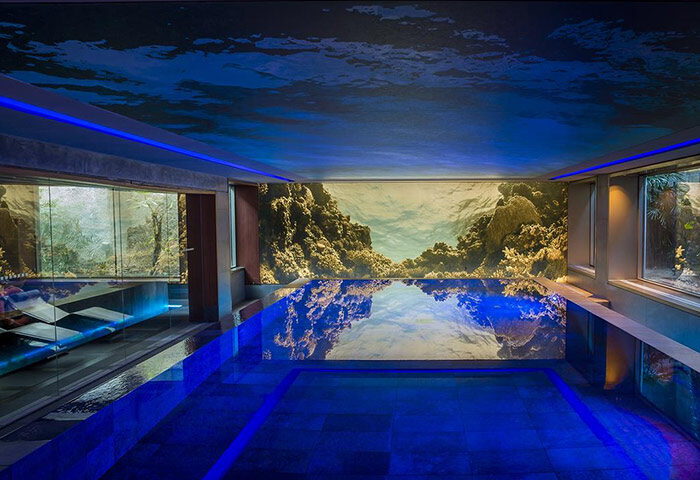 Indoor pool at Hotel MiM Sitges, a gay-friendly hotel. The pool's design features ocean-themed murals, creating a unique aquatic ambiance.