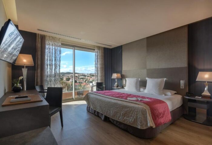 Hotel MiM Sitges gay-friendly room. Interior view with bed, desk, and balcony overlooking Sitges. Gay travel in style at this hotel.