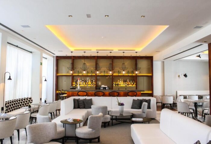 Hotel MiM Sitges gay-friendly hotel bar. Modern interior with white sofas, chairs, and a fully stocked bar. Upscale gay travel destination.