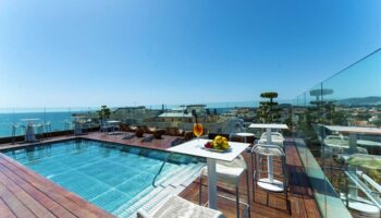 Hotel MiM Sitges gay-friendly rooftop pool. Ocean view, tables, chairs, and lounge chairs. Perfect for gay travel and relaxation.