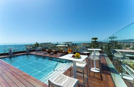 Hotel MiM Sitges gay-friendly rooftop pool. Ocean view, tables, chairs, and lounge chairs. Perfect for gay travel and relaxation.