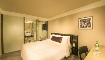 Hotel Midtown Richardson gay-friendly room. Single bed, desk, and bathroom with glass door. Modern design for gay men travelers.