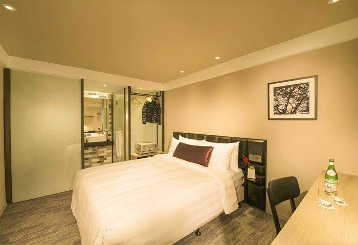 Hotel Midtown Richardson gay-friendly room. Single bed, desk, and bathroom with glass door. Modern design for gay men travelers.