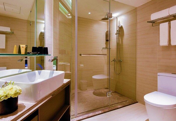 Hotel Midtown Richardson gay-friendly bathroom with glass shower, sink, and toilet. Modern design in this hotel for gay men travelers.