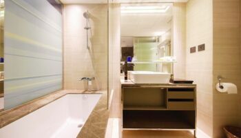 Hotel Midtown Richardson gay-friendly bathroom. Bathtub, shower, and sink with mirror. Modern design. Comfortable stay for gay travelers.