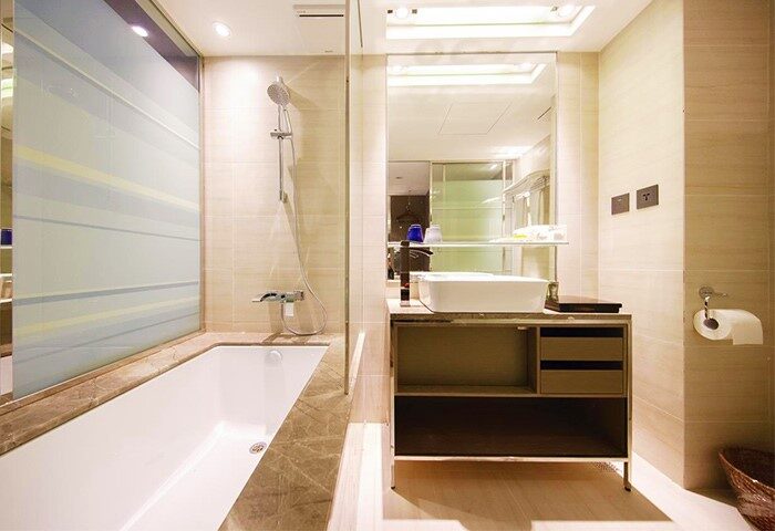 Hotel Midtown Richardson gay-friendly bathroom. Bathtub, shower, and sink with mirror. Modern design. Comfortable stay for gay travelers.