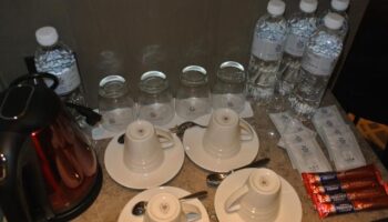 Hotel Midtown Richardson room service: kettle, cups, glasses, water bottles, coffee sticks. Gay-friendly hotel amenities.