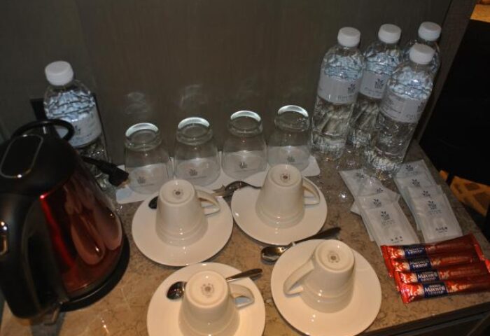 Hotel Midtown Richardson room service: kettle, cups, glasses, water bottles, coffee sticks. Gay-friendly hotel amenities.