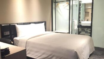 Hotel Midtown Richardson gay-friendly room. Modern design with bed, desk, and glass-enclosed bathroom. Ideal for gay travelers seeking comfort.