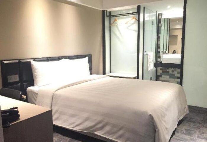 Hotel Midtown Richardson gay-friendly room. Modern design with bed, desk, and glass-enclosed bathroom. Ideal for gay travelers seeking comfort.