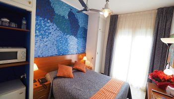 Hotel Montserrat gay-friendly room with blue decor. Cozy bedroom with double bed, blue wall art, and modern amenities. Ideal for gay travel.