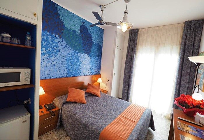 Hotel Montserrat gay-friendly room with blue decor. Cozy bedroom with double bed, blue wall art, and modern amenities. Ideal for gay travel.