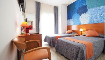 Hotel Montserrat gay-friendly room with two beds, colorful wall art, and modern amenities. Comfortable lodging for gay men travelers.
